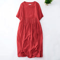 A red short-sleeve dress with a pleated waist, laid flat on a white background with a small green plant in the top right corner, Obroi