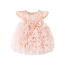 A baby girl's formal dress in a soft peach-pink color, featuring a satin bodice with flutter sleeves and a large matching bow at the center, paired with a tiered ruffled tulle skirt, shown on a plain white background, Obroi