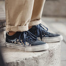 Blue sneakers with white soles worn by a person sitting on concrete steps, Obroi