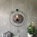 Decorative wall clock with a light bulb on a gray wall with a plant and books in the foreground, Obroi