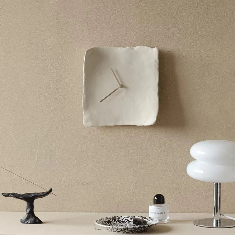 Square wall clock on a beige wall with minimal decor, Obroi