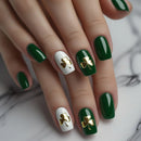 Close-up of a hand with green nails featuring gold shamrock designs on a white background, Obroi