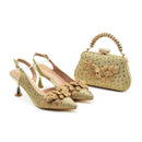 Gold high-heeled shoes and matching handbag with floral designs on a white background, Obroi