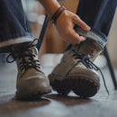 Person wearing brown boots with laces, sitting on a chair, Obroi