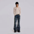 Person wearing a beige long-sleeve shirt and blue jeans on a plain background, Obroi