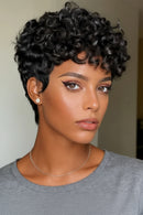 Woman with short, curly black hair wearing a gray shirt indoors, Obroi