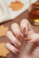 Nails with gold feather and flower designs on a blurred background, Obroi