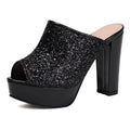 A single black platform mule sandal with a chunky block heel, featuring a glittery black upper and a light beige insole, shown against a plain white background, Obroi