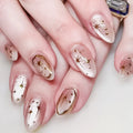 Nails with star and gold design on a white background, Obroi