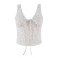 A sleeveless white camisole top with a delicate multicolor floral print, featuring a scalloped V-neckline, a front tie closure, and a drawstring hem, shown against a plain white background, Obroi
