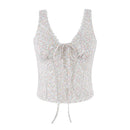 A sleeveless white camisole top with a delicate multicolor floral print, featuring a scalloped V-neckline, a front tie closure, and a drawstring hem, shown against a plain white background, Obroi