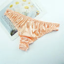 Peach-colored lace-trimmed underwear on a light surface with a magazine in the background, Obroi