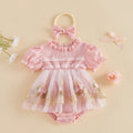 A baby girl's pink short-sleeve romper with a ruffled collar, lace trim, and a floral tulle skirt, shown with a matching pink bow headband on a beige background with decorative flowers, Obroi