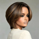 A woman wearing a short layered bob wig with dark brown and warm brown highlights, shown from a three-quarter back view against a plain gray studio background, Obroi