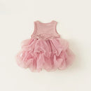 A baby girl's sleeveless tutu dress in dusty pink, featuring a ribbed knit bodice and a layered, ruffled tulle skirt, laid flat on a light cream background, Obroi