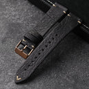 Black leather watch strap with rose gold buckle on a dark textured surface, Obroi