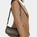 Person wearing a brown coat with a black handbag on a white background, Obroi