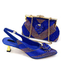 A royal blue embellished women's slingback heeled shoe with a matching beaded clutch handbag, both decorated with gold rhinestones and floral embellishments, set against a plain white background, Obroi