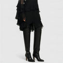 Black leather knee-high boots worn with a black ruffled dress on a white background, Obroi