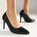 Black high-heeled shoes worn by a person on a light background, Obroi