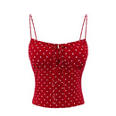 Red camisole top with white polka dots, featuring thin shoulder straps, a sweetheart neckline, and a front tie closure, shown against a plain white background, Obroi