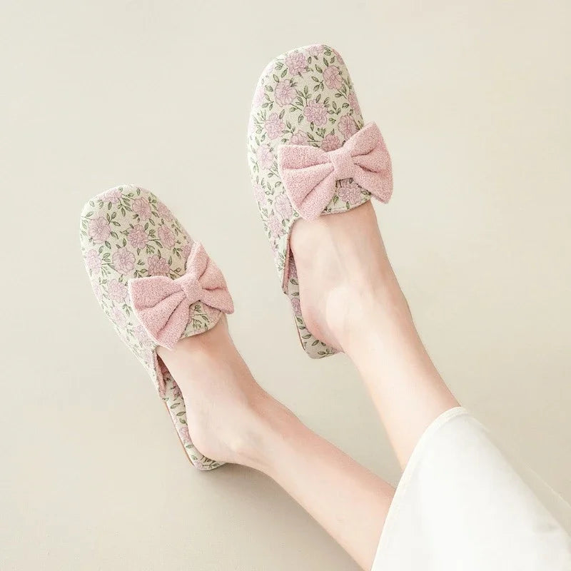Floral slippers with pink bows worn by a person on a light background, Obroi