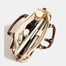 Beige bag with brown straps containing electronic devices on a light gray background, Obroi
