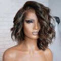 A medium-length wavy wig with dark brown and black roots and warm brown highlights, styled on a mannequin head against a white brick wall background. The brand logo 'Obroi' is visible in the top left corner, Obroi