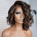 A medium-length wavy wig with dark brown and black roots and warm brown highlights, styled on a mannequin head against a white brick wall background. The brand logo 'Obroi' is visible in the top left corner, Obroi
