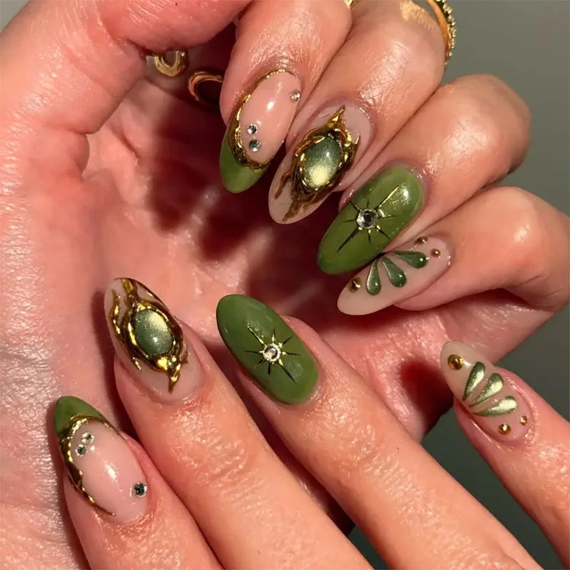 Close-up of a hand with green and gold nail art on a neutral background, Obroi.