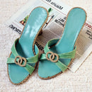Pair of turquoise sandals with green straps on a textured surface with a newspaper underneath, Obroi