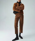 Person wearing a brown fuzzy sweater and pants with black shoes on a light gray background, Obroi