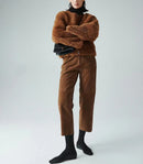 Person wearing a brown fuzzy sweater and pants with black shoes on a light gray background, Obroi