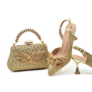 Gold handbag and high-heeled shoes with floral designs on a white background, Obroi