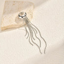 Silver ring with tassel on a textured beige surface, Obroi