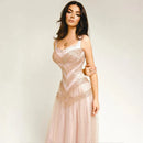 A woman modeling a pale blush pink evening gown with intricate beaded corset-style detailing and a flowing tulle skirt, photographed against a plain light background. The word Obroi appears in the top left corner, Obroi
