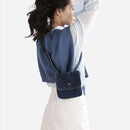 Woman wearing a blue denim bag over her shoulder on a white background, Obroi