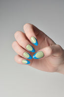 Hand with light green and blue nail polish on a neutral background, Obroi