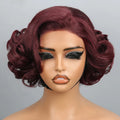 A short, voluminous wavy wig in a deep burgundy shade displayed on a mannequin head against a light gray background, with a black label reading, Obroi