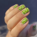 Close-up of a hand with green nail art on a blurred background, Obroi