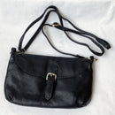 Black leather handbag with a strap on a light gray background, Obroi