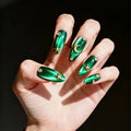 Hand with green nail art featuring stars and moons on a dark background, Obroi