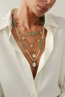 Necklace with green beads and gold pendants on a white shirt background, Obroi