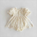 A cream-colored baby dress with delicate lace and floral embroidery, featuring short ruffled sleeves, a buttoned neckline, and a flared skirt, laid flat on a light gray background, Obroi