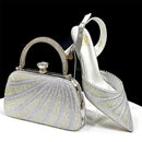 Silver clutch bag and high-heeled shoe with intricate designs on a white surface, Obroi