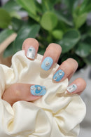 Close-up of a hand with decorative nail art featuring blue and silver designs, Obroi