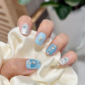 Close-up of a hand with decorative nail art featuring blue and silver designs, Obroi