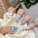 Close-up of a hand with decorative nail art featuring blue and silver designs, Obroi