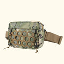 A tactical waist bag with a green and brown camouflage pattern, featuring a tan honeycomb-patterned front panel and an adjustable tan webbing strap, shown against a solid cream background, Obroi