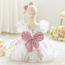 White dress with pink floral patterns and a large bow on a mannequin against a light background.Obroi